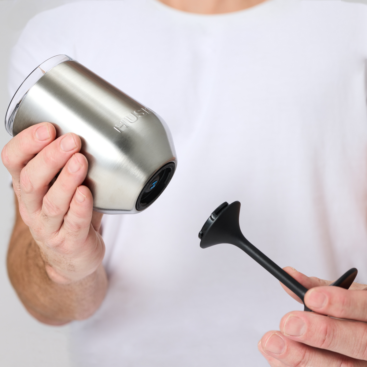 Person holding a stainless steel Huski Wine Tumbler 2.0, showing the base ready to attach the detachable stem held in their other hand